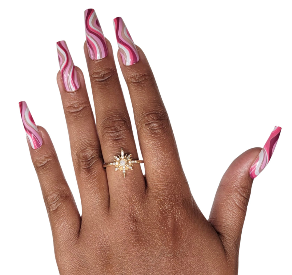 Model Wearing Casket Ready Beauty's Coffin-shaped long-length glossy beige nude, baby pink, hot pink, purplish pink, and white swirl abstract nails. 