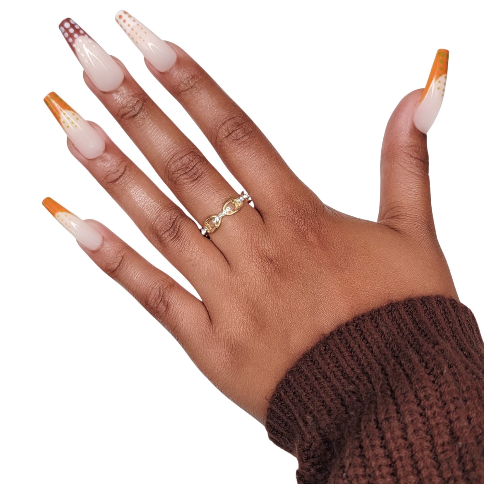 Model Wearing Casket Ready Beauty's Coffin-shaped long neutral-colored nails with orange, brown, and white French tips and orange, white, and green polka dots.