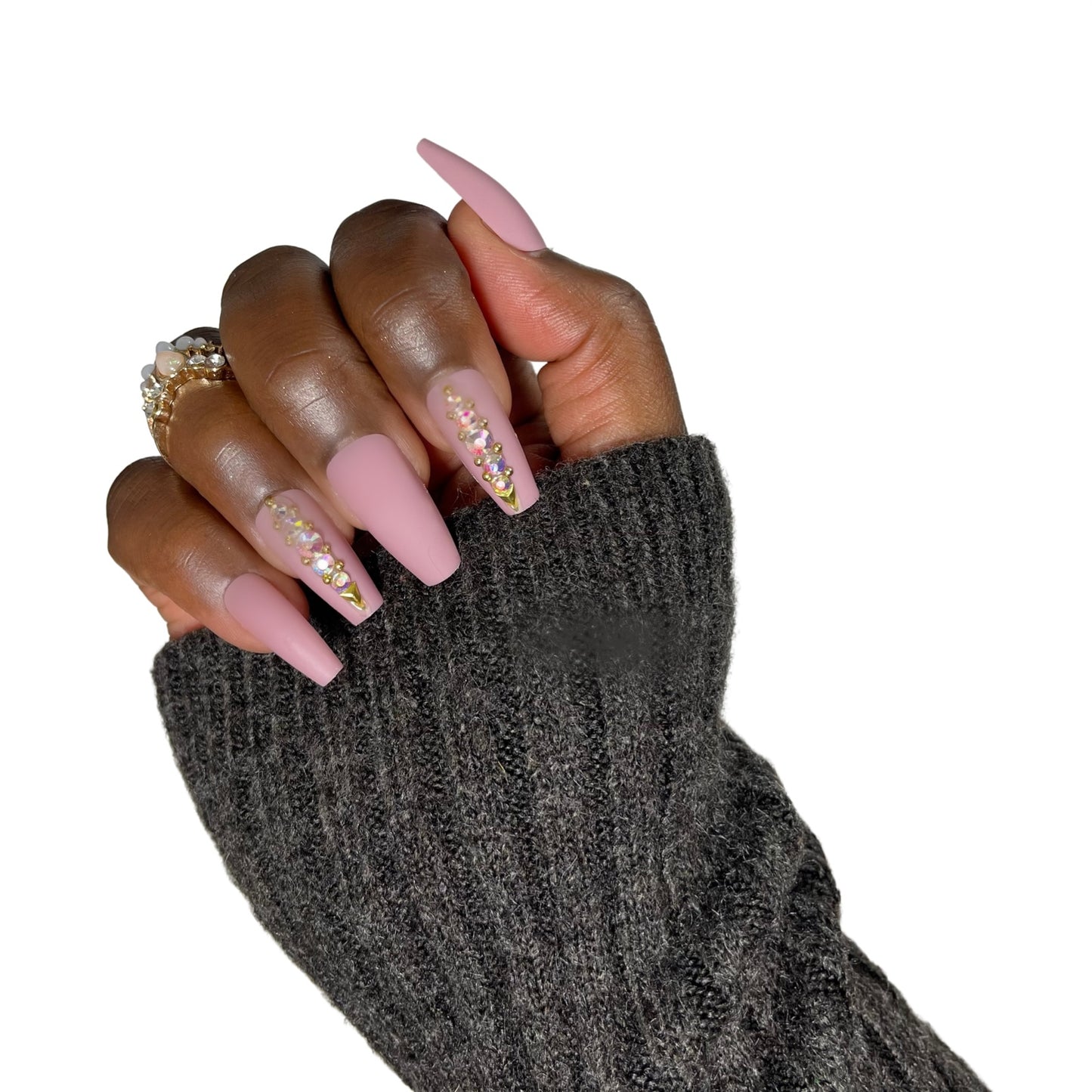 Model Wearing Casket Ready Beauty's Coffin-shaped medium-length matte dark solid pinkish beige nails, with decorated accent nails with rhinestones, gold caviar beads, and gold triangle gems.